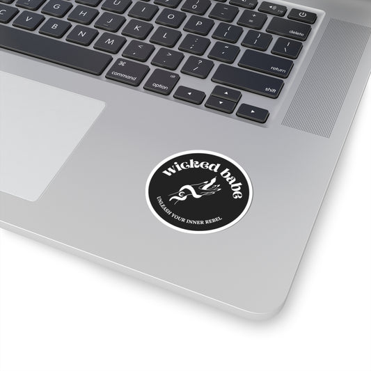 2 inch charcoal circular sticker with 'wicked babe' hand with serpent logo in white with a white border on a laptop