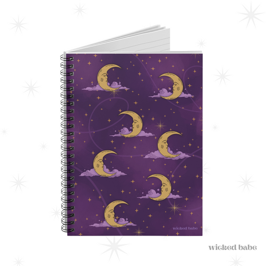 Slightly opened spiral hardcover notebook with purple celestial sky with gold crescent moon and stars