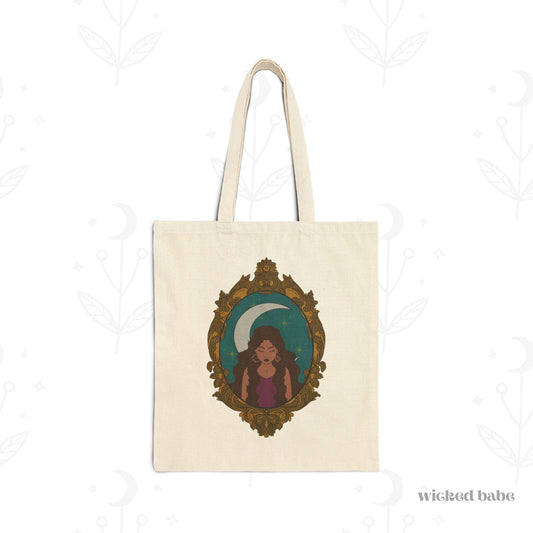 Canvas tote bag with design of a tan skinned woman with brown wavy hair wearing purple in front of large crescent moon on a teal background surrounded by ornate gold frame