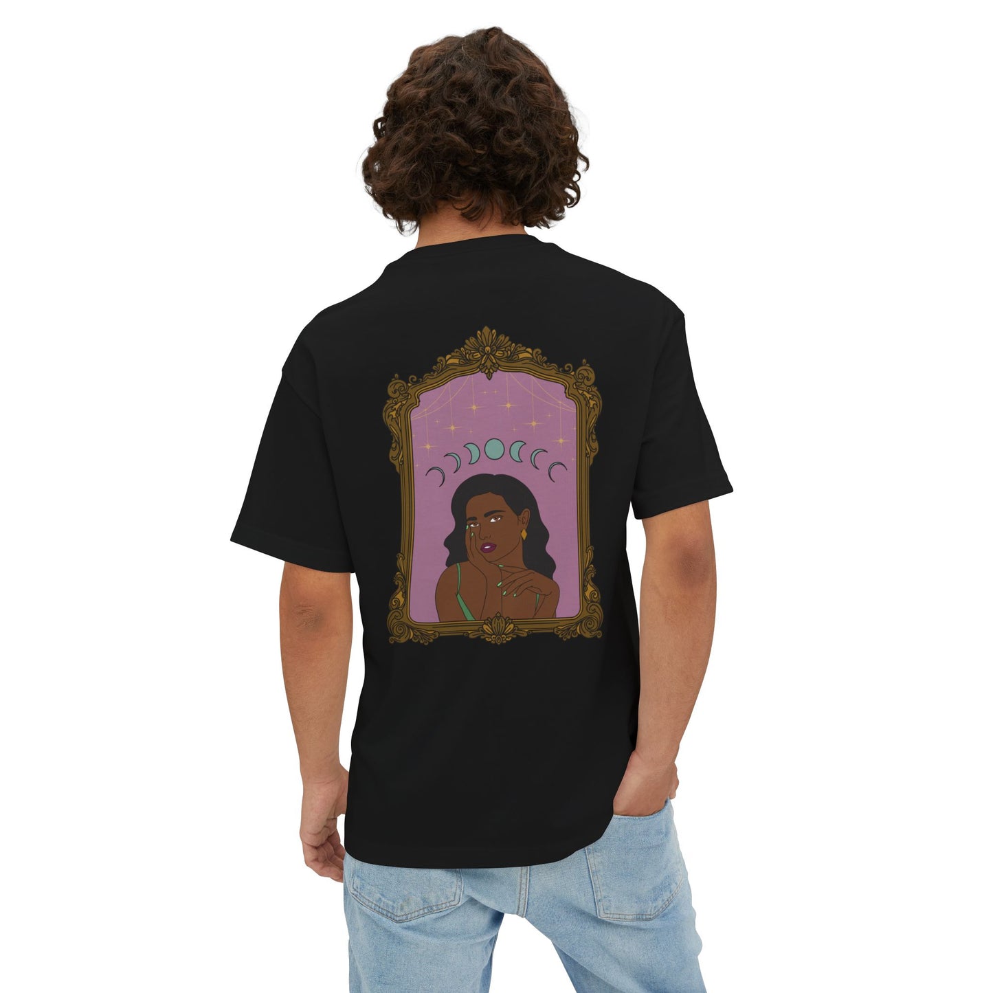Man wearing an oversized short sleeve black t-shirt with design of a dark skinned woman with black hair wearing green on a pink background with moon phases above surrounded by ornate gold frame on the back