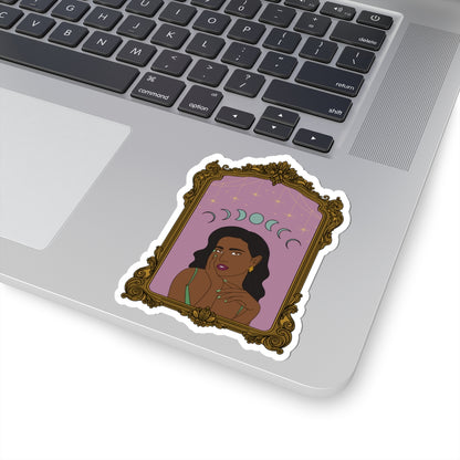 4 inch sticker with design of a dark skinned woman with black hair wearing green on a pink background with moon phases above surrounded by ornate gold frame with a white border on a laptop