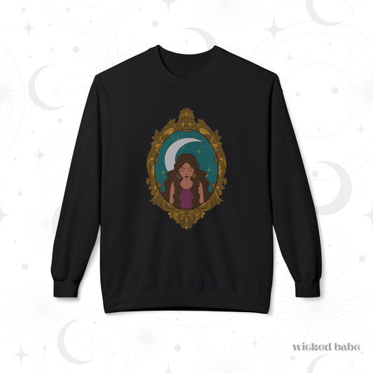 Black long sleeve crewneck sweatshirt with design of a tan skinned woman with brown wavy hair wearing purple in front of large crescent moon on a teal background surrounded by ornate gold frame