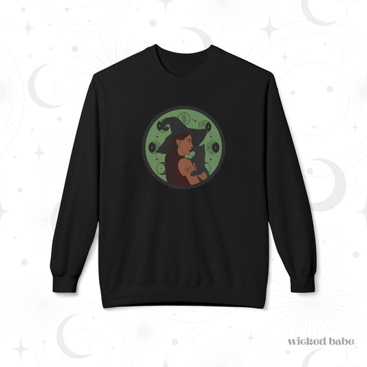 Black crewneck long sleeve pullover sweatshirt featuring a design of a woman wearing a witch's hat holding a gray cat with moon phases on a green background