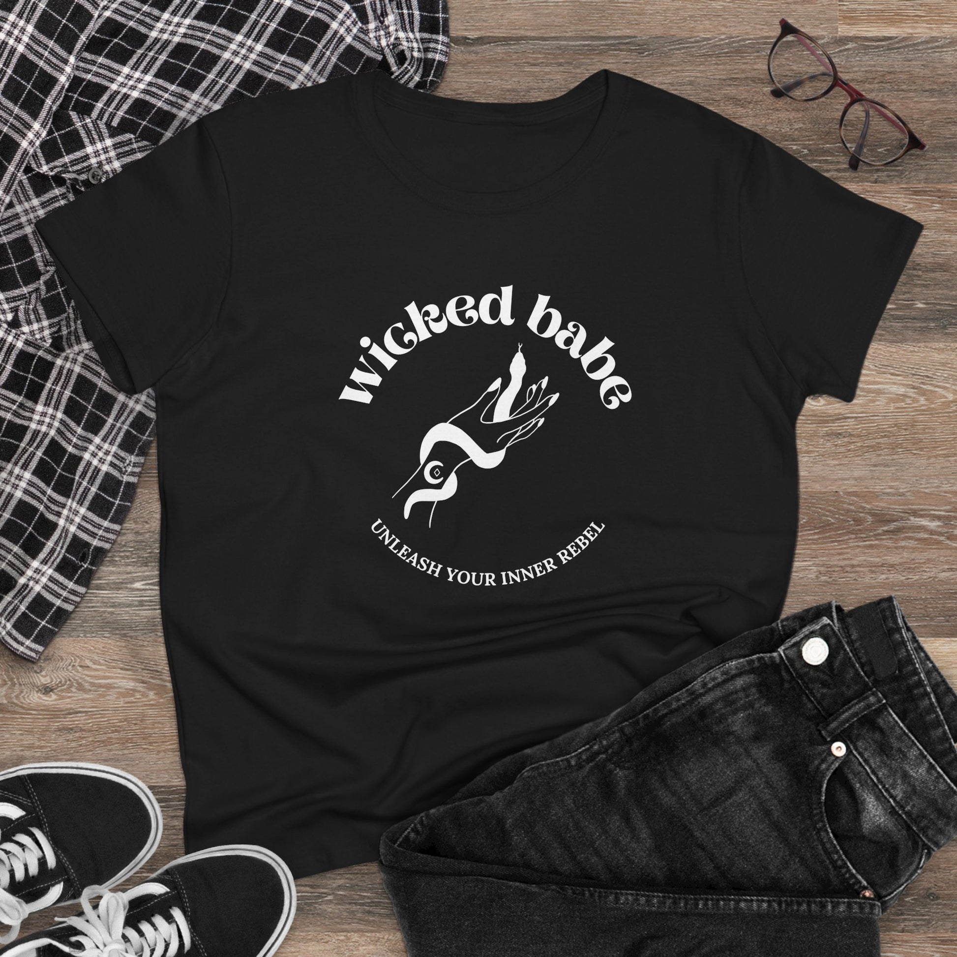 Black short sleeve crewneck t-shirt with wicked babe hand with serpent logo in white on the front on a wooden surface with jeans and sneakers.
