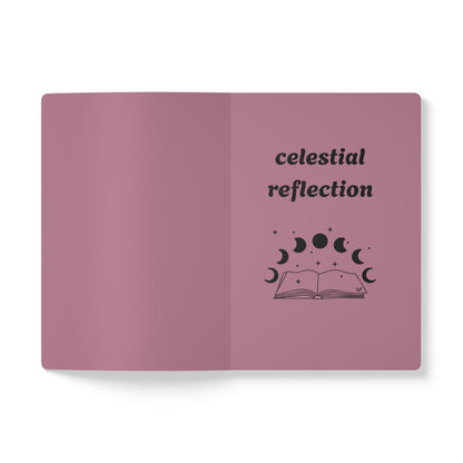 Inside first page of pink journal notebook with celestial reflection text in black and a book with moon phases graphic