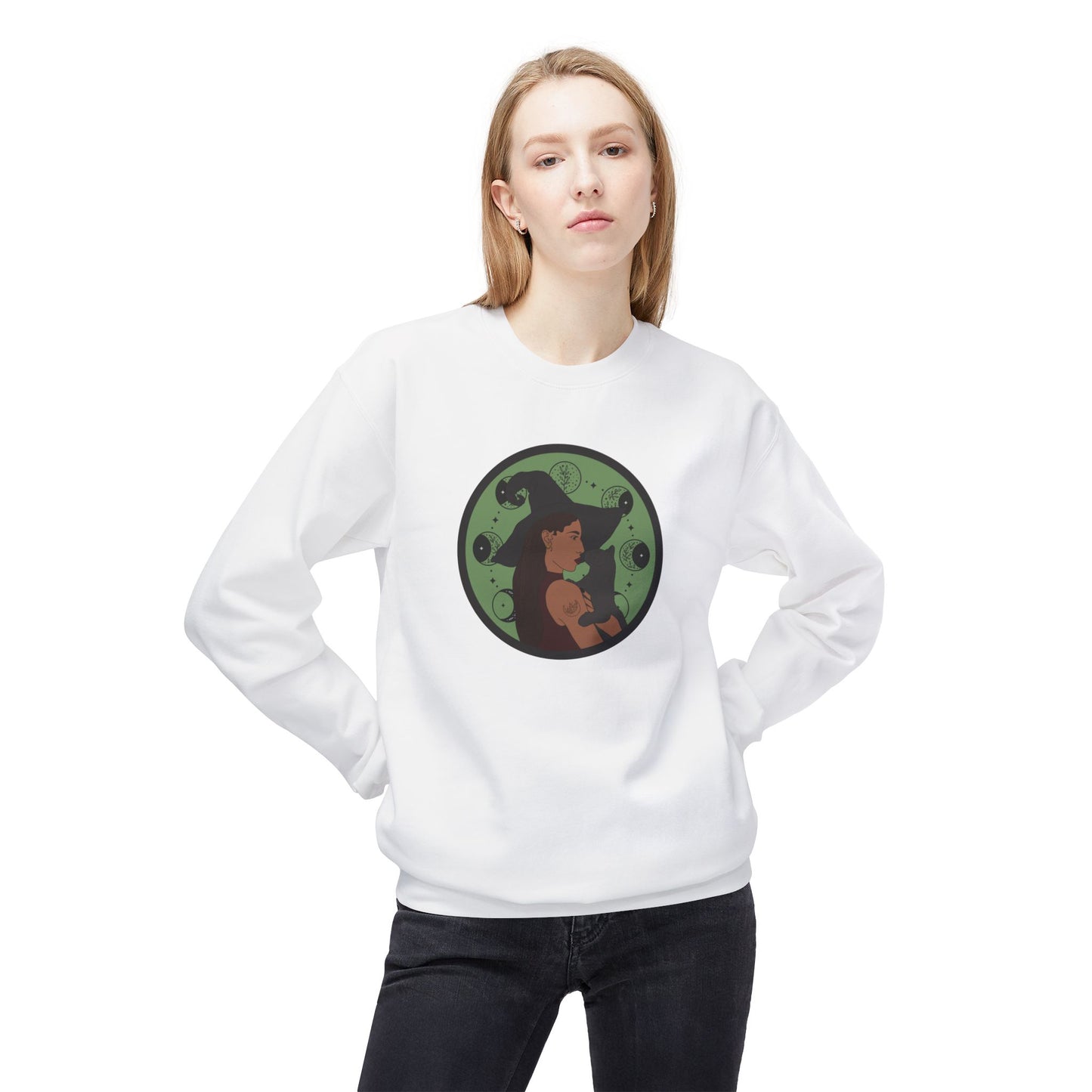 Woman wearing a white crewneck long sleeve pullover sweatshirt featuring a design of a woman wearing a witch's hat holding a gray cat with moon phases on a green background