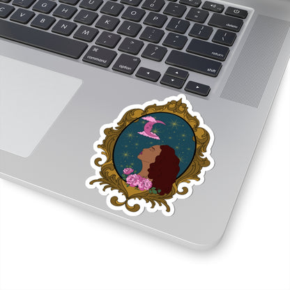 4 inch sticker with design of a tan skinned woman with red brown wavy hair with pink flowers and a pink crescent moon above on a teal background surrounded by an ornate gold frame with a white border on a laptop