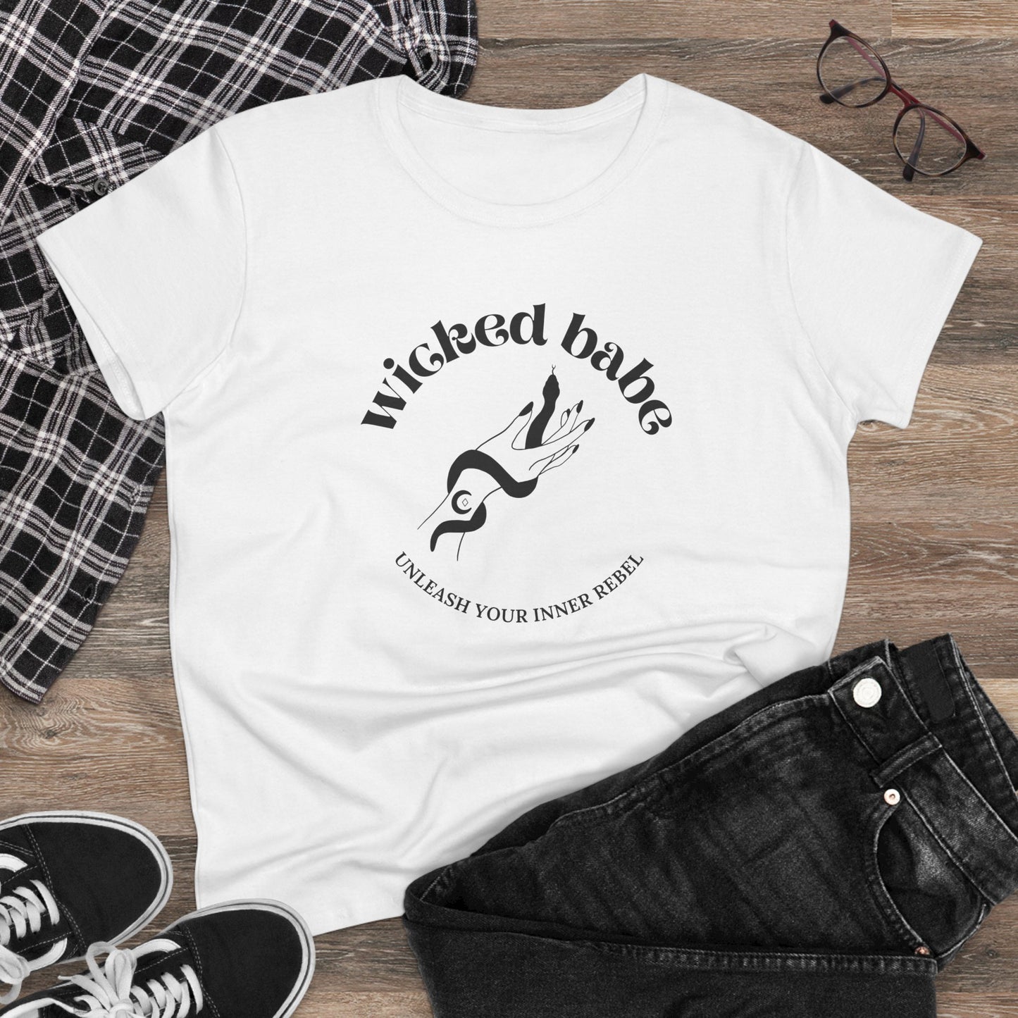 White short sleeve crewneck t-shirt with wicked babe hand with serpent logo in black on the front on a wooden surface with jeans and sneakers.