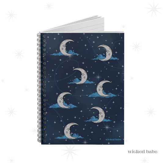 Slightly opened spiral hardcover notebook with blue celestial sky with silver crescent moon and stars