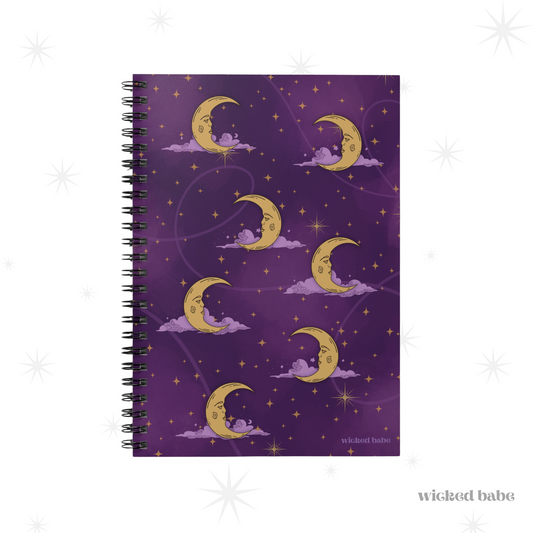 The front of a spiral hardcover notebook with purple celestial sky with gold crescent moon and stars