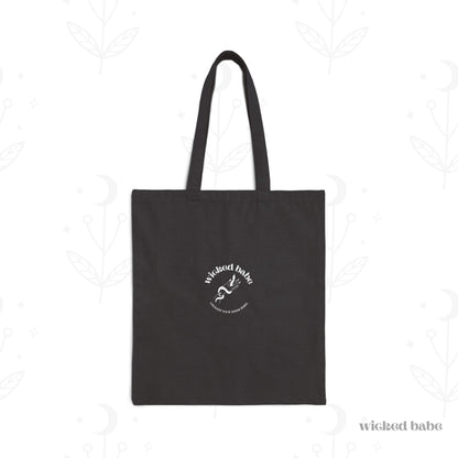 The back of a black tote bag with white wicked babe hand with serpent logo in the center