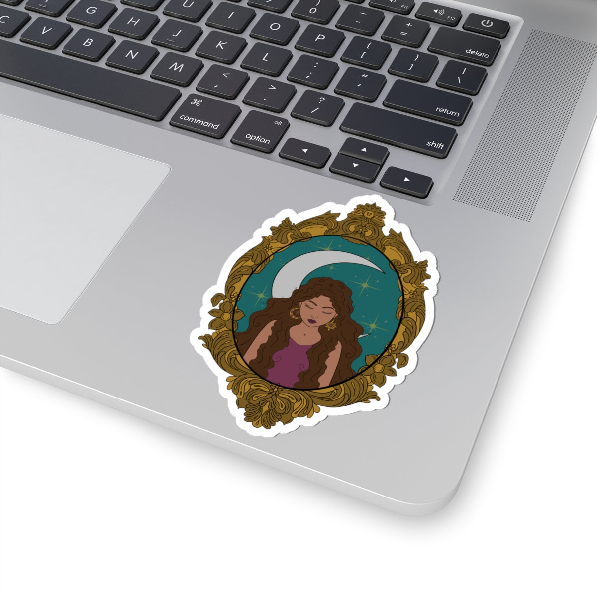 4 inch sticker with design of a tan skinned woman with brown wavy hair wearing purple in front of large crescent moon on a teal background surrounded by ornate gold frame with a white border on a laptop
