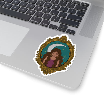 4 inch sticker with design of a tan skinned woman with brown wavy hair wearing purple in front of large crescent moon on a teal background surrounded by ornate gold frame with a white border on a laptop