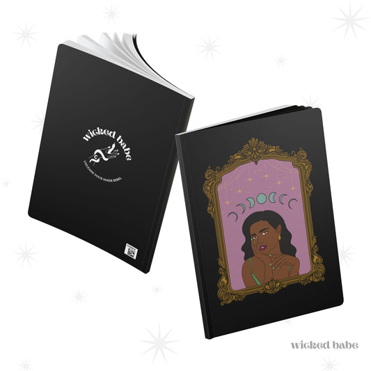 Front and back cover of black softcover journal notebook with design of a dark skinned woman with black hair wearing green on a pink background with moon phases above surrounded by ornate gold frame on the front and white wicked babe hand with serpent logo in the center on the back