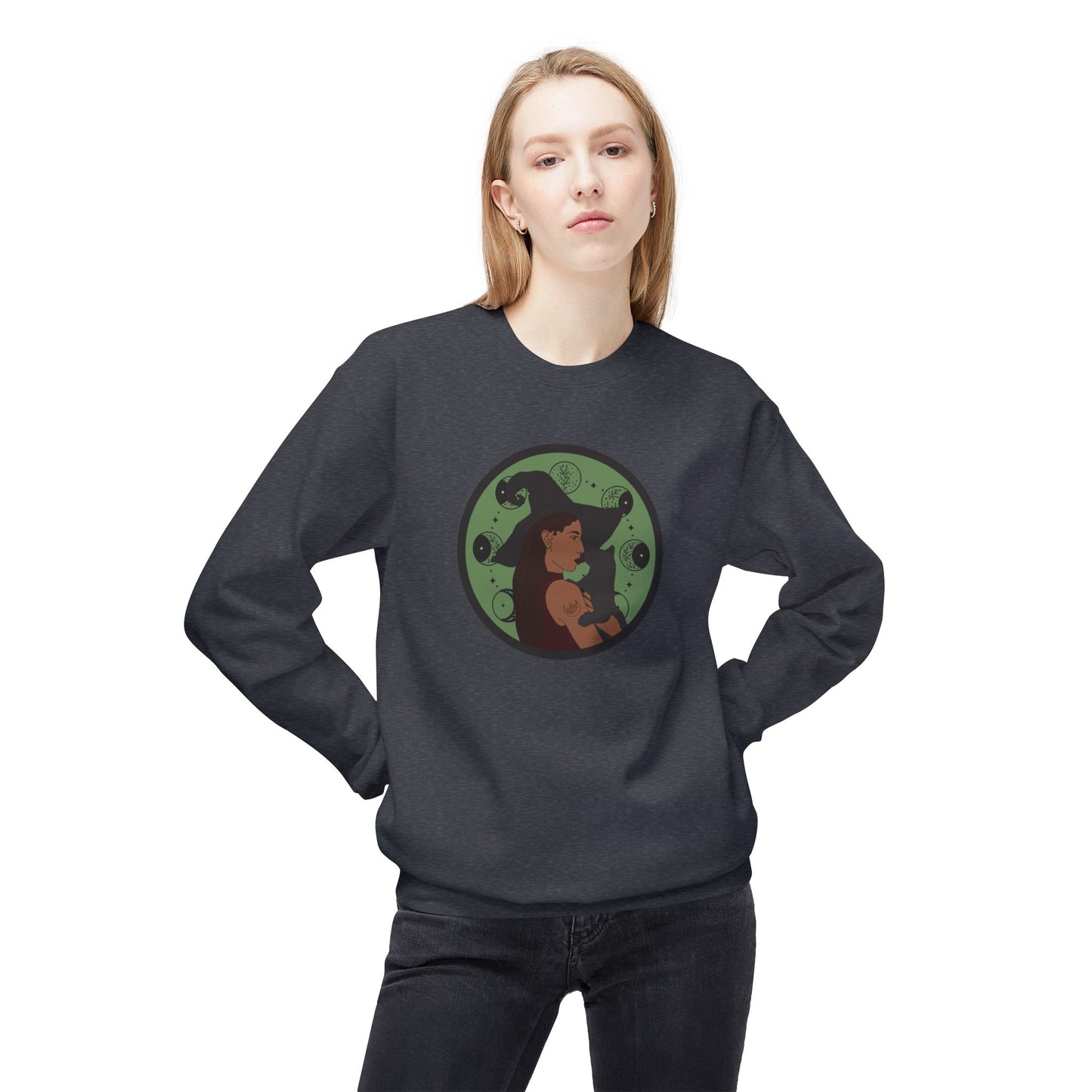 Woman wearing a dark heather gray crewneck long sleeve pullover sweatshirt featuring a design of a woman wearing a witch's hat holding a gray cat with moon phases on a green background