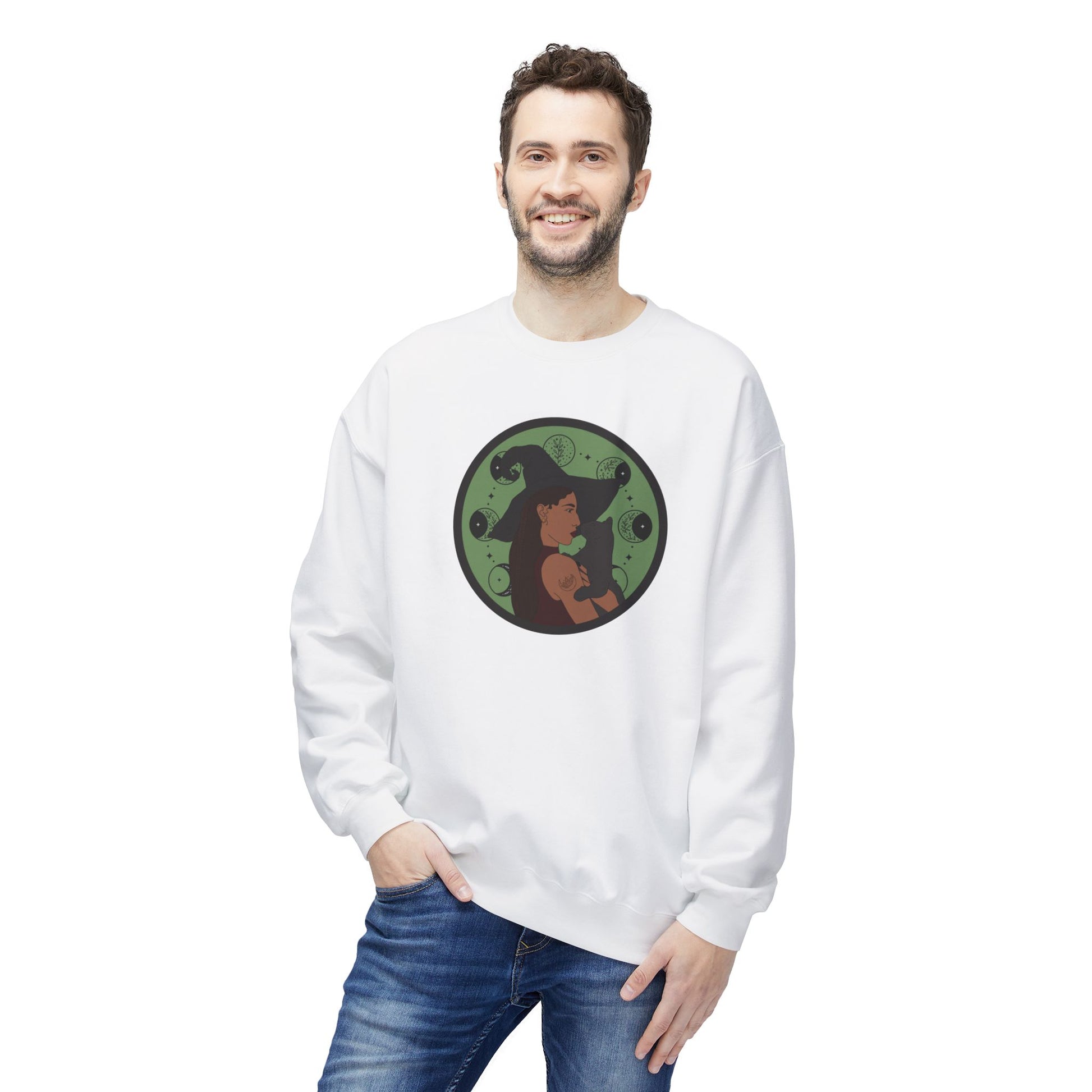 Man wearing a white crewneck long sleeve pullover sweatshirt featuring a design of a woman wearing a witch's hat holding a gray cat with moon phases on a green background