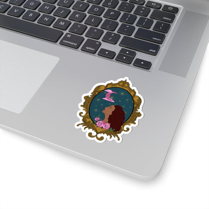 3 inch sticker with design of a tan skinned woman with red brown wavy hair with pink flowers and a pink crescent moon above on a teal background surrounded by an ornate gold frame with a white border on a laptop