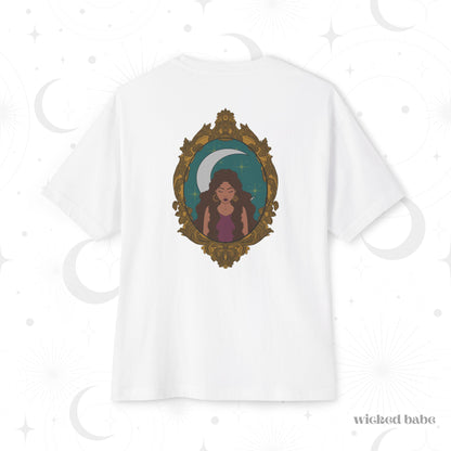 Oversized short sleeve white t-shirt with a design of a tan skinned woman with brown wavy hair wearing purple in front of large crescent moon on a teal background surrounded by ornate gold frame on the back