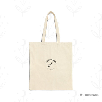 The back of a canvas tote bag with black wicked babe hand with serpent logo in the center