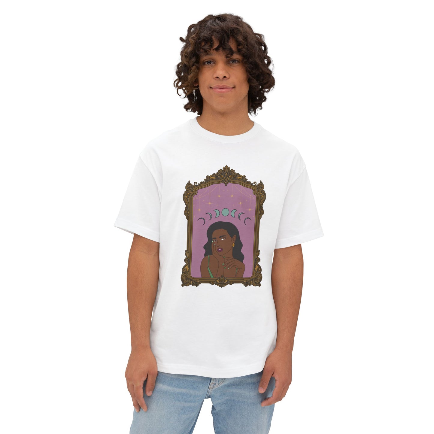 Man wearing an oversized short sleeve white t-shirt with design of a dark skinned woman with black hair wearing green on a pink background with moon phases above surrounded by ornate gold frame
