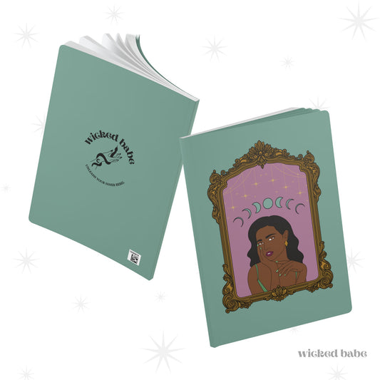 Front and back cover of green softcover journal notebook with design of a dark skinned woman with black hair wearing green on a pink background with moon phases above surrounded by ornate gold frame on the front and black wicked babe hand with serpent logo in the center on the back