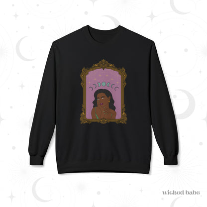 Black long sleeve crewneck sweatshirt with design of a dark skinned woman with black hair wearing green on a pink background with moon phases above surrounded by ornate gold frame