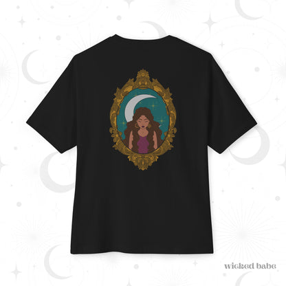 Oversized short sleeve black t-shirt with a design of a tan skinned woman with brown wavy hair wearing purple in front of large crescent moon on a teal background surrounded by ornate gold frame on the back